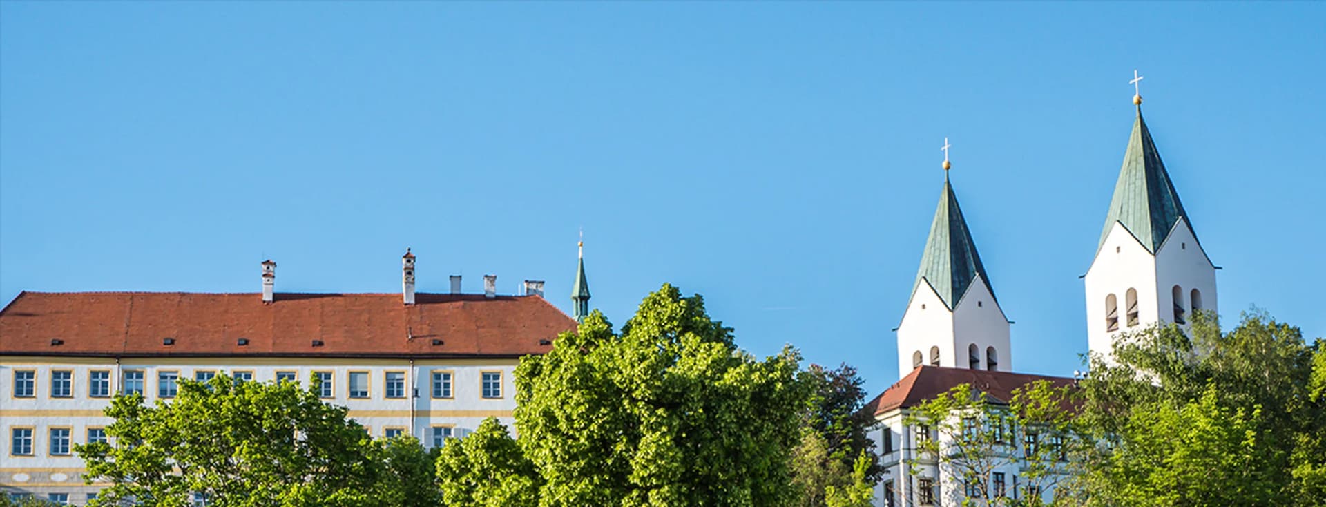 Towers of Freising Cathedral overlooking green landscapes – living in Freising with nature and city flair