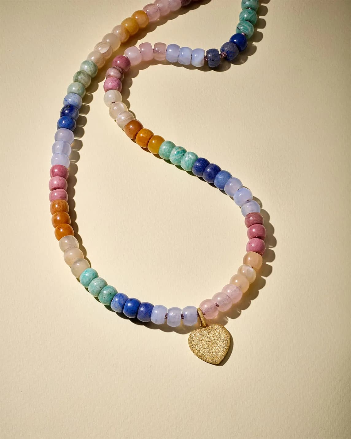 Colorful beaded necklace made of round pastel stones with a gold heart pendant.