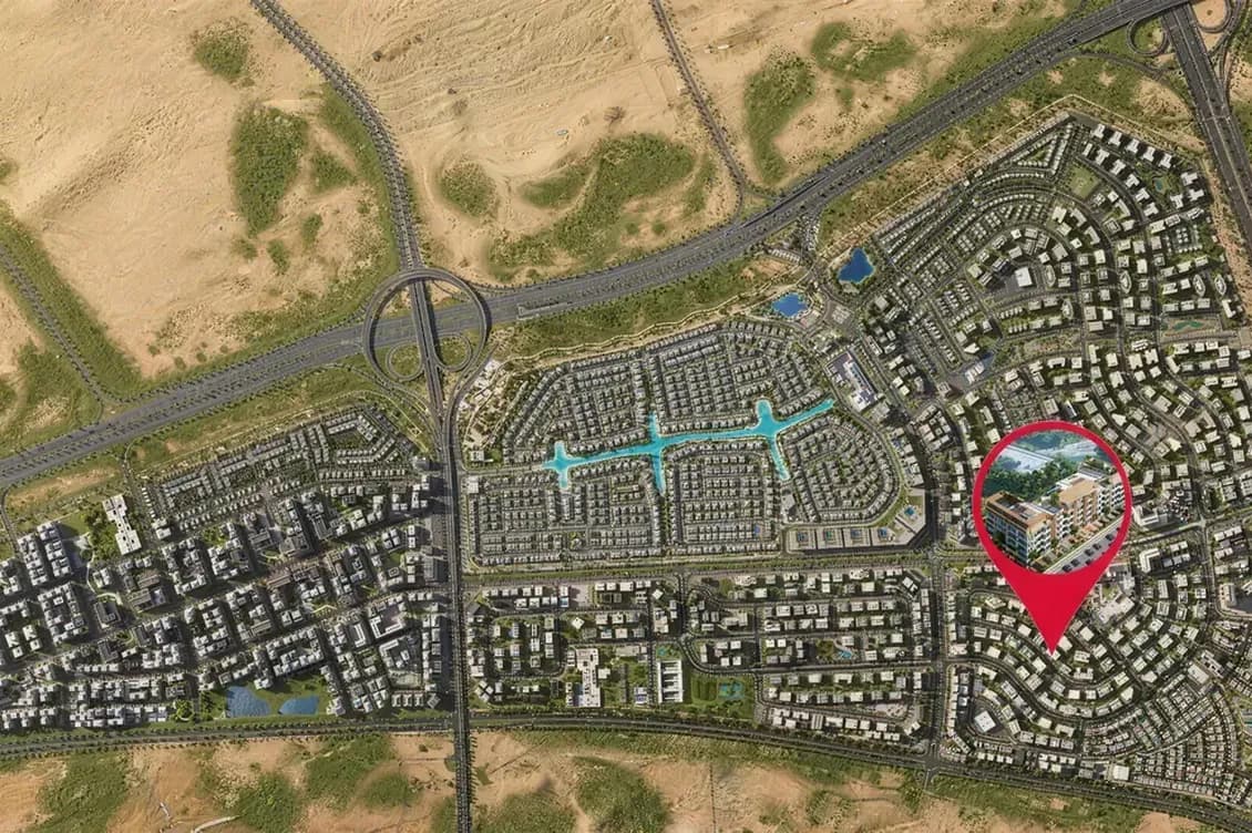 Aerial view of a desert suburb with winding roads, roundabouts, and a red pin highlighting a mid-rise building.