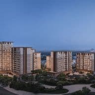 A cluster of modern high-rise residential buildings at dusk, surrounded by greenery with a city skyline in the distant background.