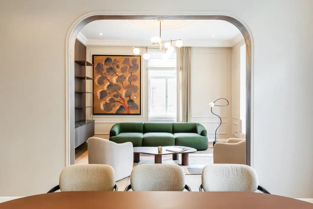 Bright living room with a green sofa, armchairs, modern lighting and a large statement artwork.