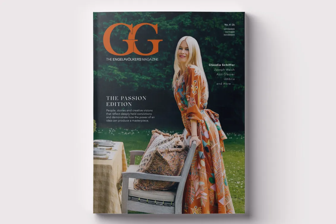 A magazin címlapján egy szőke nő látható narancssárga mintás ruhában, a szabadban, egy étkezőasztal és szék melMagazine cover featuring a blonde woman in an orange patterned dress outdoors beside a dining table and chair, with a bold orange GG logo.