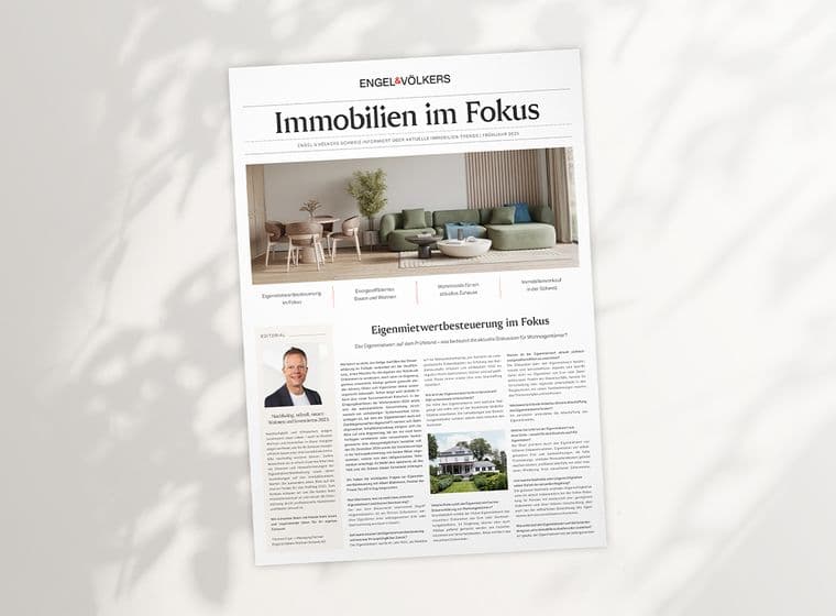 A newspaper titled "Immobilien im Fokus" with articles and images about real estate, featuring a modern living room and a portrait of a person.