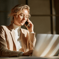 Woman talking on the phone, in front of a laptop, under direct sunlight.