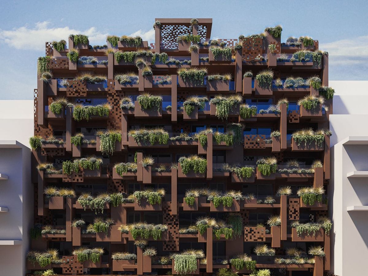 Brown modular building facade with stacked box-like balconies filled with grasses and trailing plants against a clear blue sky.