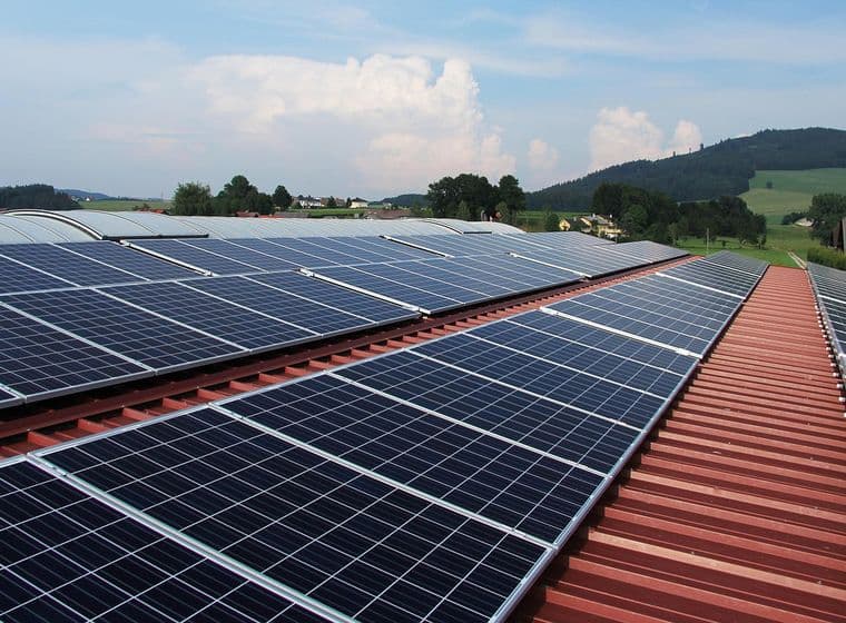 Blick über das Dach einer Gewerbeimmobilie mit Solarpanel in grüner, hügeliger Landschaft
