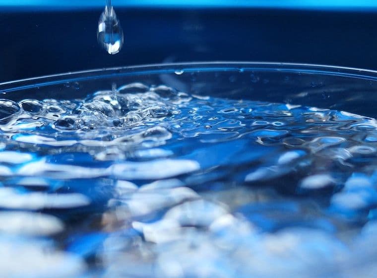 Nahaufnahme von Wasser in einem Glas in Bewegung, ein Tropfen fällt hinein
