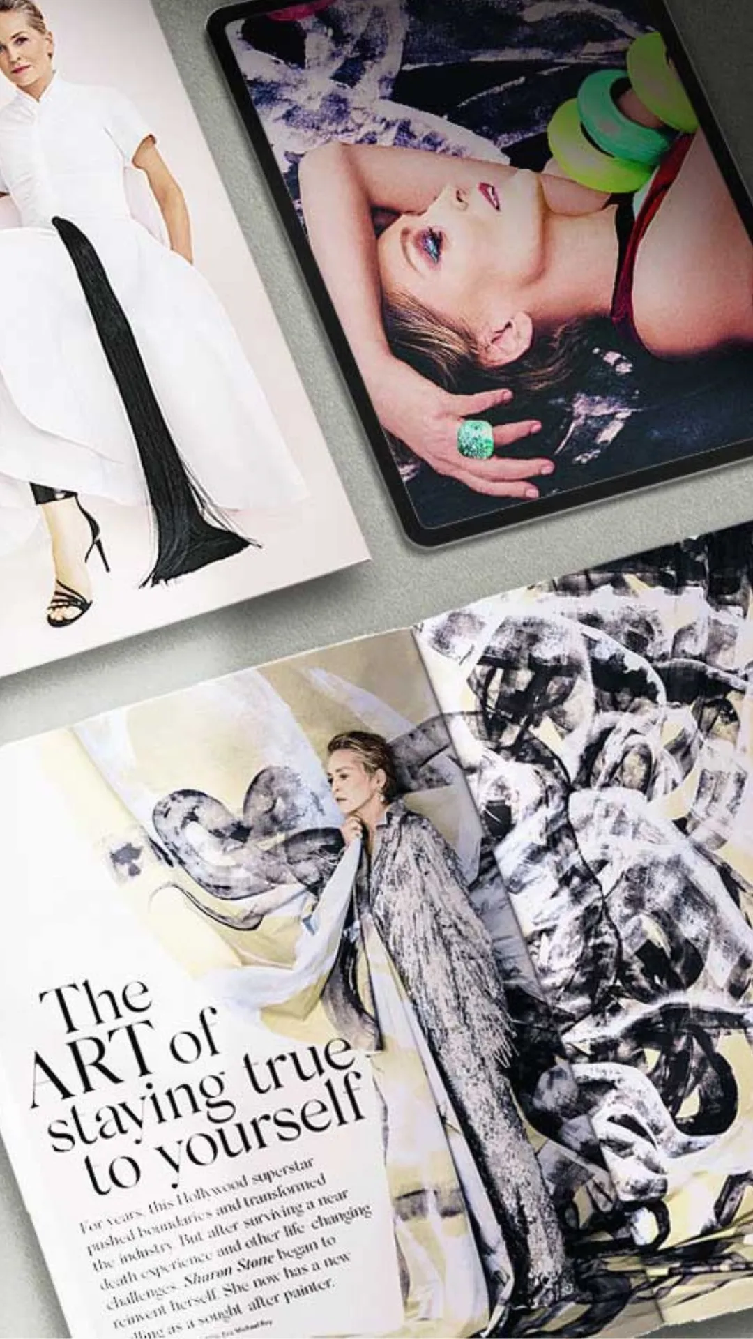 A flat lay photograph of fashion magazines and a tablet on a gray surface, featuring a model, the headline “LIVING LEGENDS,” and abstract art.