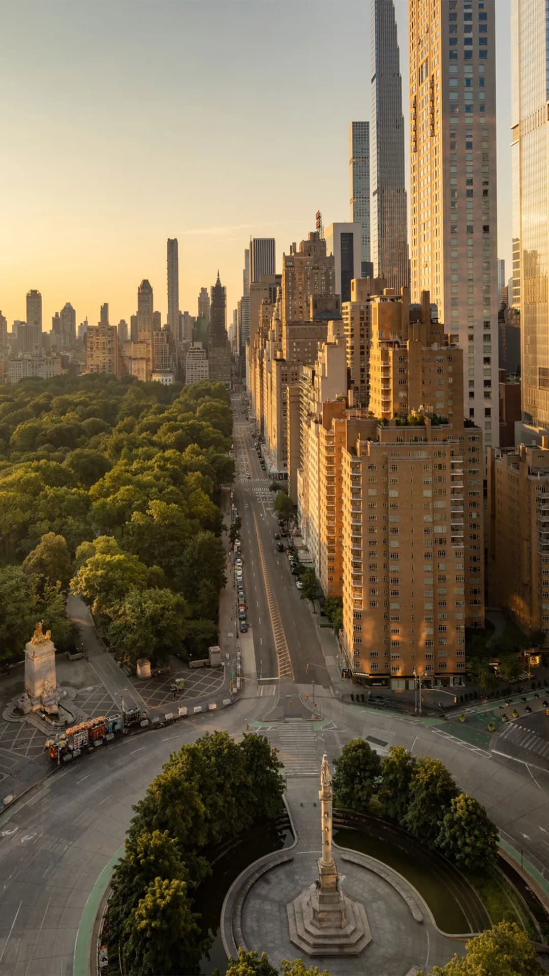 Panoramic city skyline at sunset with golden light reflecting off tall skyscrapers on the right and Central Park sprawling left.