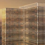 Two glass-clad office towers connected by a sky bridge, bathed in sunset light with warm reflections on grid-like windows.