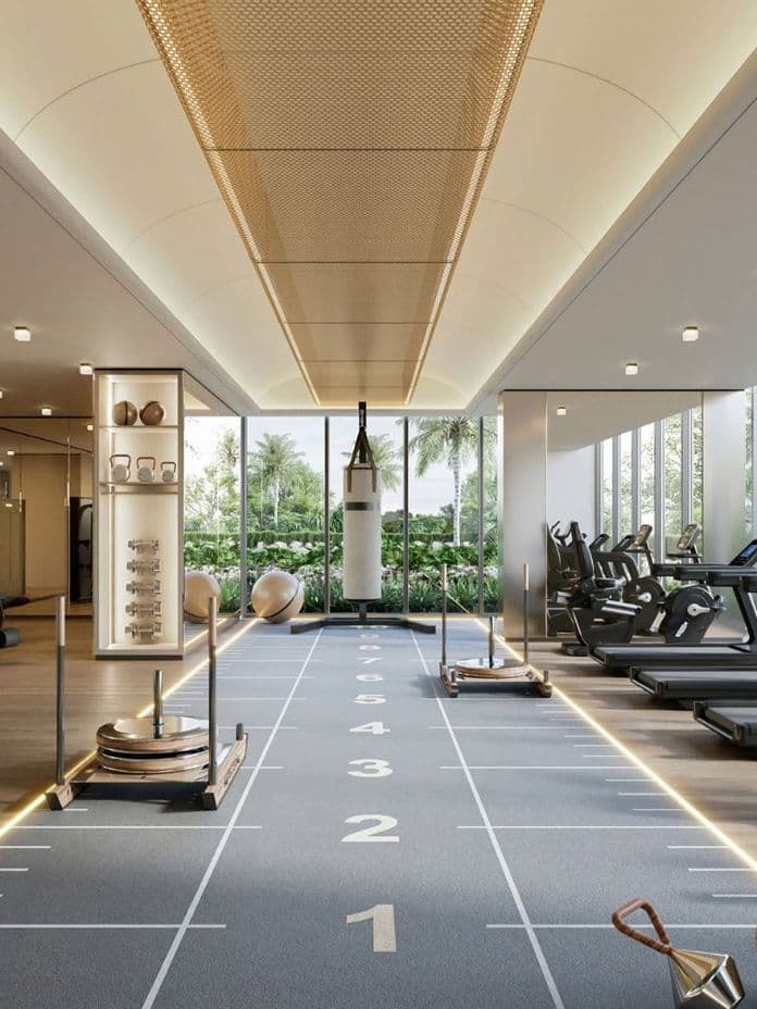 Modern gym with treadmills, exercise equipment, and a boxing bag; large windows offer a view of lush greenery outside.