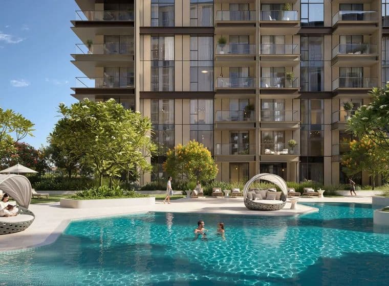 Modern apartment building with glass balconies, trees, and a pool. People are swimming and relaxing around the pool on a sunny day.