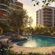 Sunset over a resort-style apartment complex with a curved turquoise pool, lounge chairs, and modern high-rise buildings.