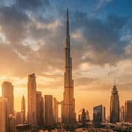 Skyline of Dubai at sunset with Burj Khalifa in the center, surrounded by modern skyscrapers under a partly cloudy sky.