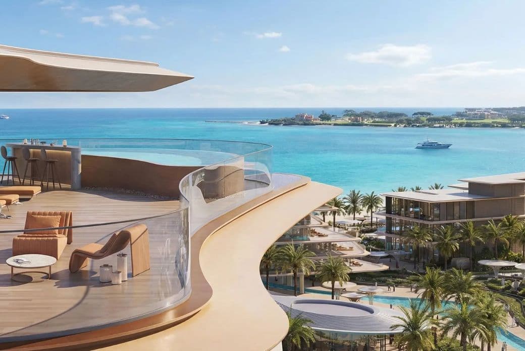A luxurious beachfront resort with curved balcony, elegant furniture, palm trees, and a boat on turquoise water under a clear blue sky.