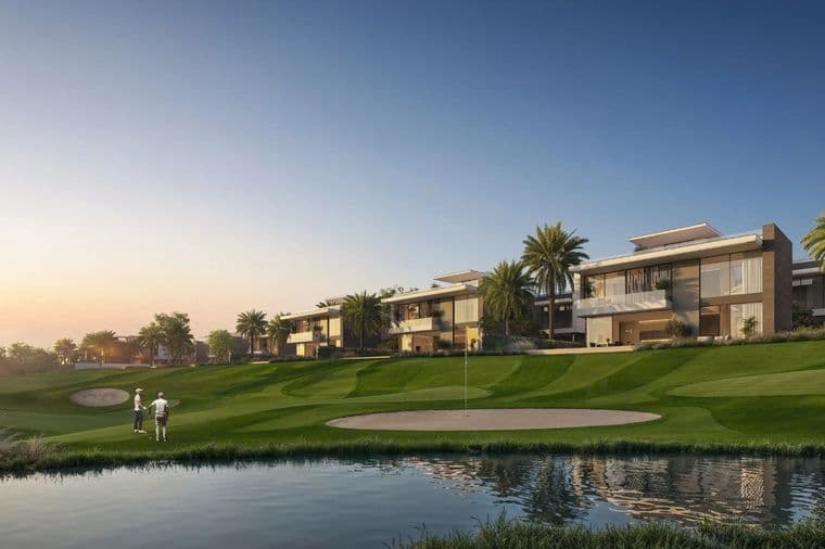 Golf course with two players near a sand trap, modern houses, and palm trees in the background under a clear blue sky.