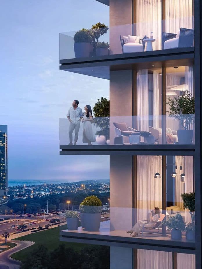 Couple standing on a modern high-rise balcony at dusk, city skyline in background, with warm interior lights and a seated couple on a lower balcony.