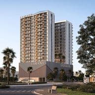Two modern high-rise buildings with glass balconies, surrounded by palm trees, under a clear blue sky. A bench is in the foreground.