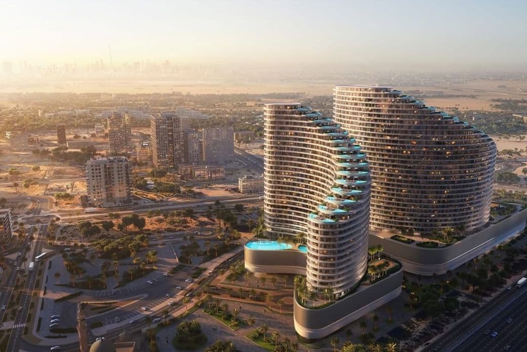 Aerial view of modern, curvy apartment buildings with rooftop pools, set against a sprawling cityscape at sunset.