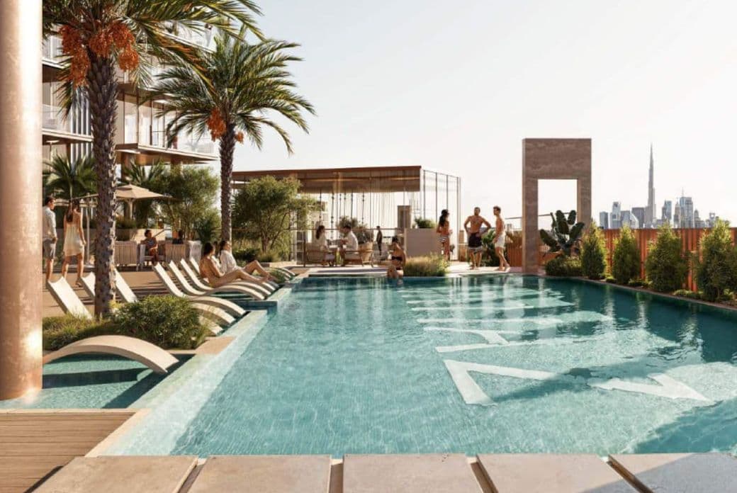 Rooftop pool with lounge chairs and palm trees overlooking a city skyline. People are relaxing by the pool.