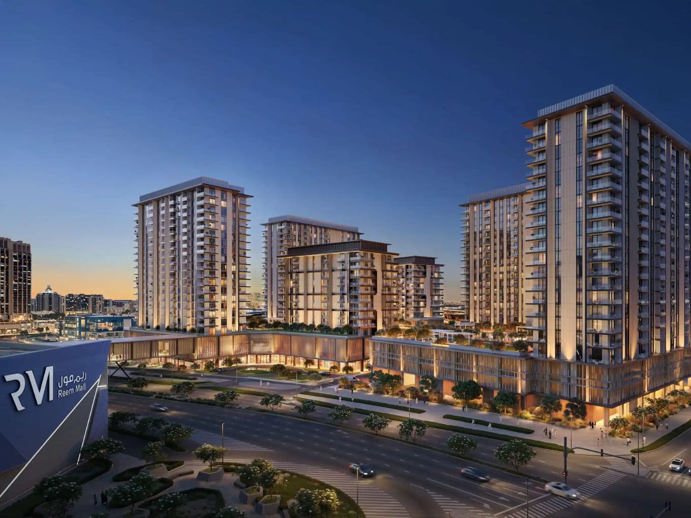 Modern cityscape at dusk featuring illuminated high-rise buildings, a busy road, and trees, with a prominent building on the left side.