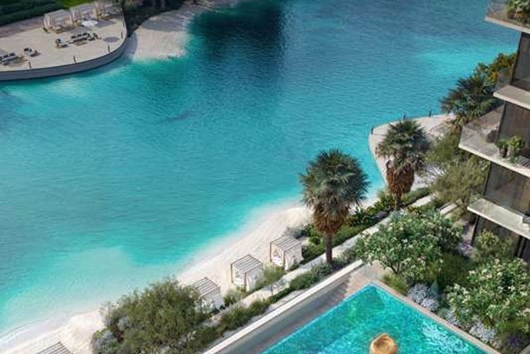 Turquoise lagoon with white sand and palm trees; terraced buildings overlook the water, while a pool in the foreground shows a hat floating. KI-generiertes Bild