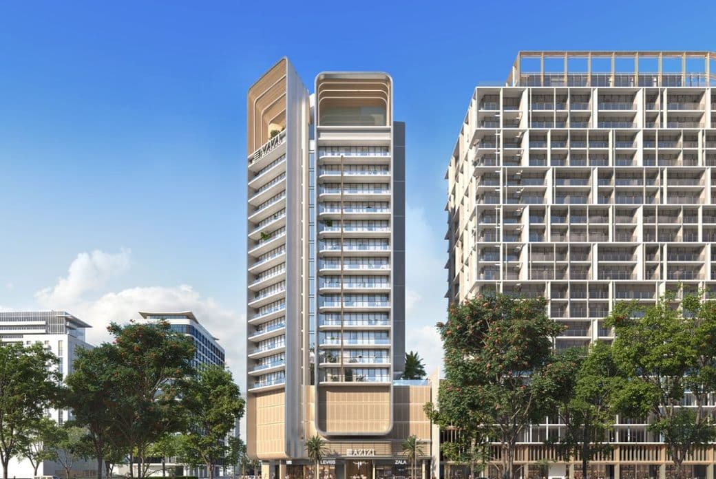 Modern high-rise building with a sleek design, flanked by trees and surrounded by urban structures under a clear blue sky.