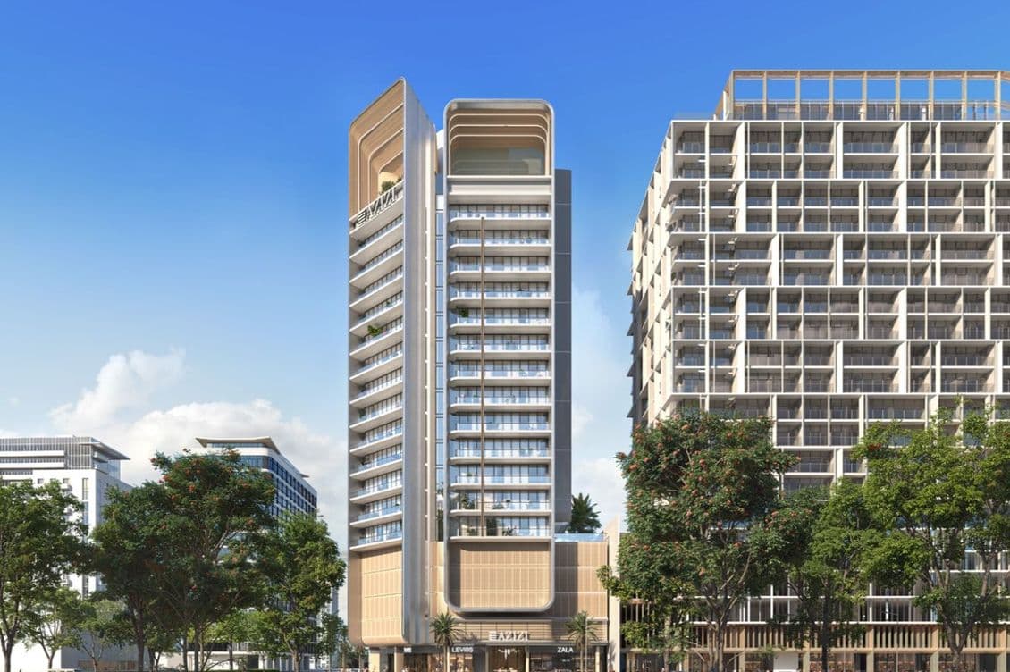 Modern high-rise building with a sleek design, flanked by trees and surrounded by urban structures under a clear blue sky.