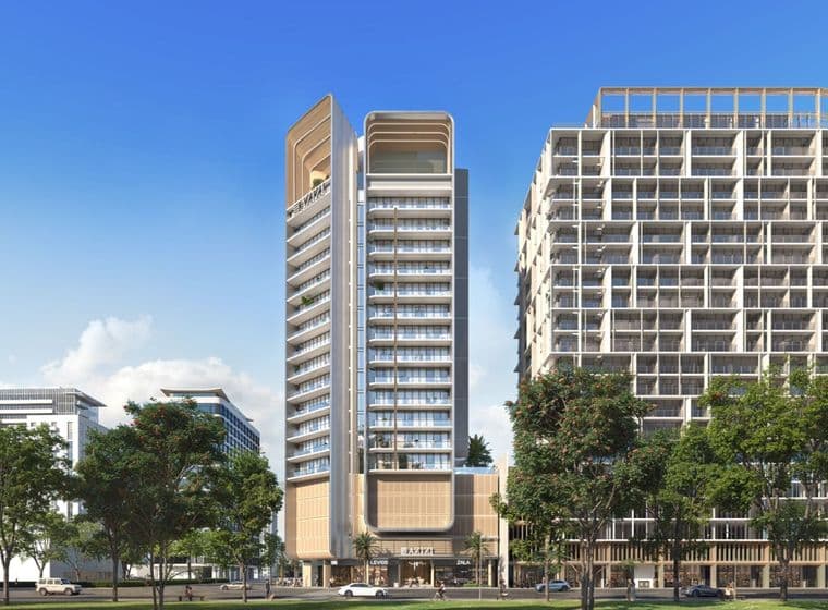 Modern high-rise building with a sleek design, flanked by trees and surrounded by urban structures under a clear blue sky.
