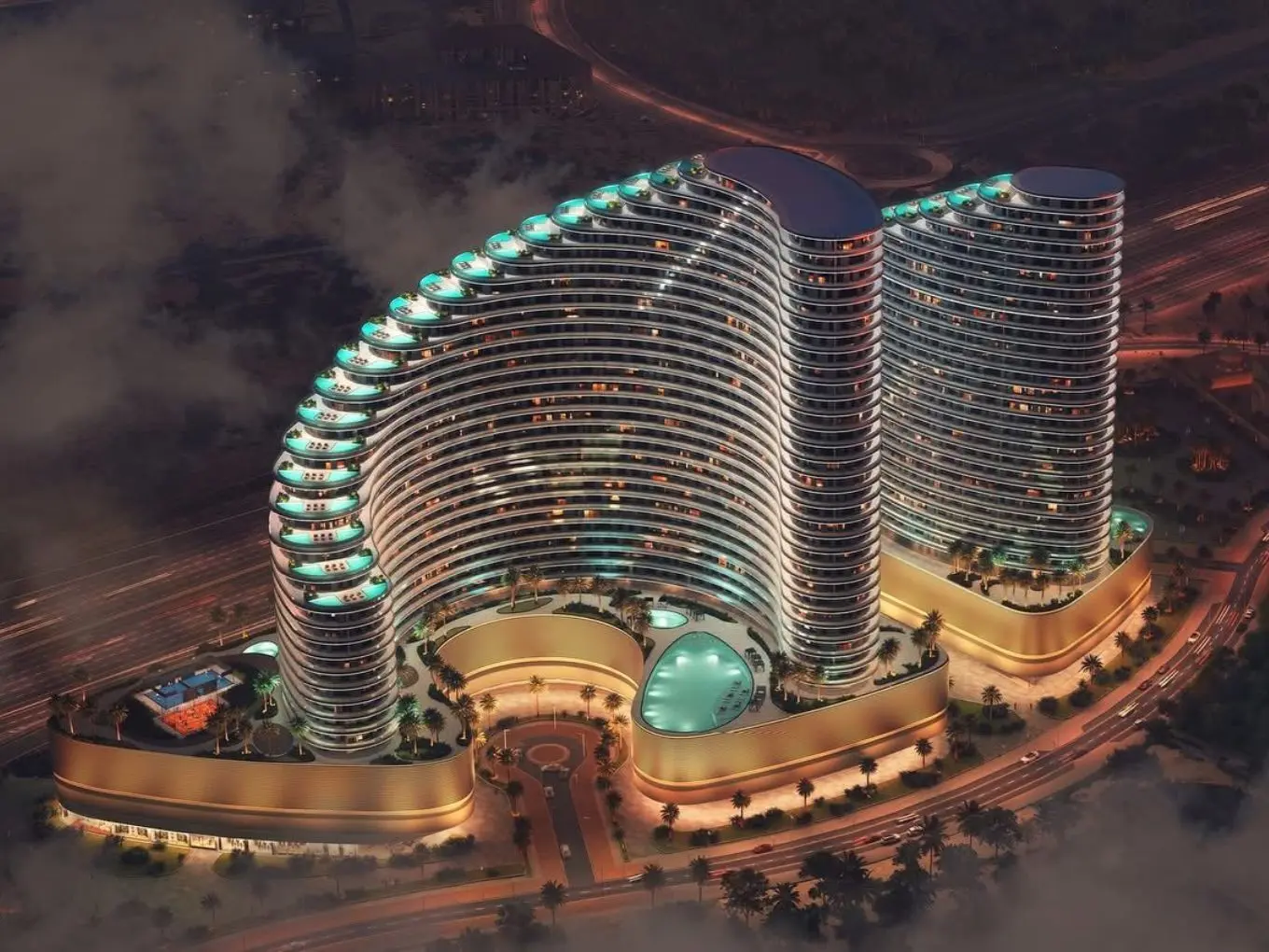 Aerial view of a modern, illuminated twin-tower complex with curved architecture, circular central pool, and surrounding roads at dusk.