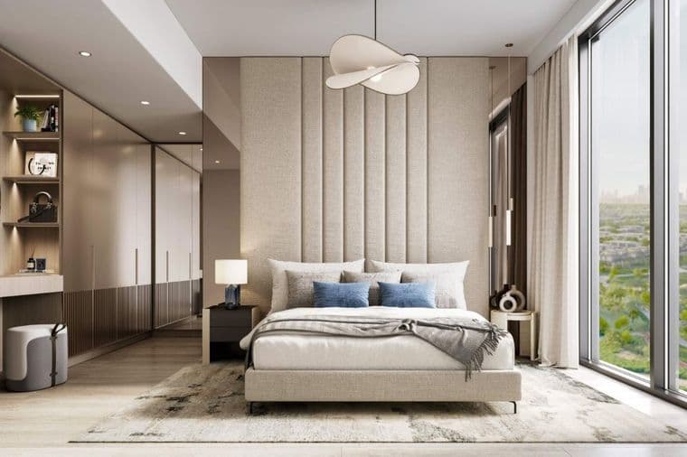 Modern bedroom with large window, beige tones, upholstered headboard, double bed, blue cushions, and contemporary hanging light fixture.