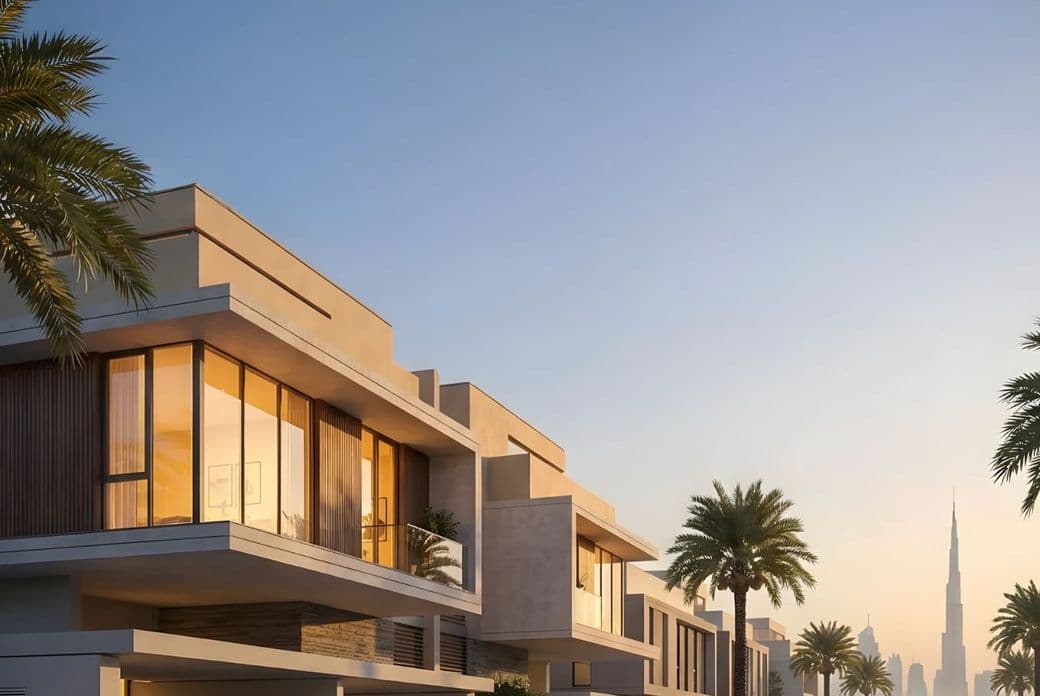 Modern villas with large windows at sunset, surrounded by palm trees, with a distant city skyline featuring a tall tower.