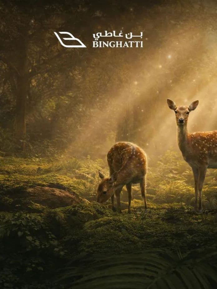 Two deer in a sunlit forest clearing, with soft rays of light filtering through trees. BINGHATTI logo in the top center.