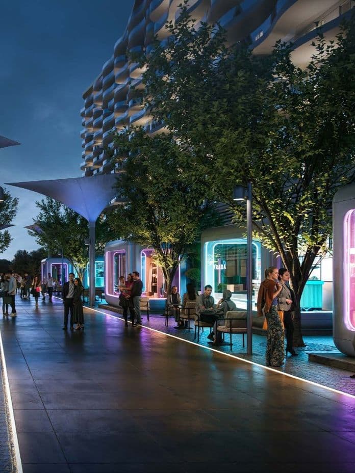 A futuristic outdoor shopping area at night with neon-lit stores, modern architecture, and people strolling and socializing under illuminated structures.