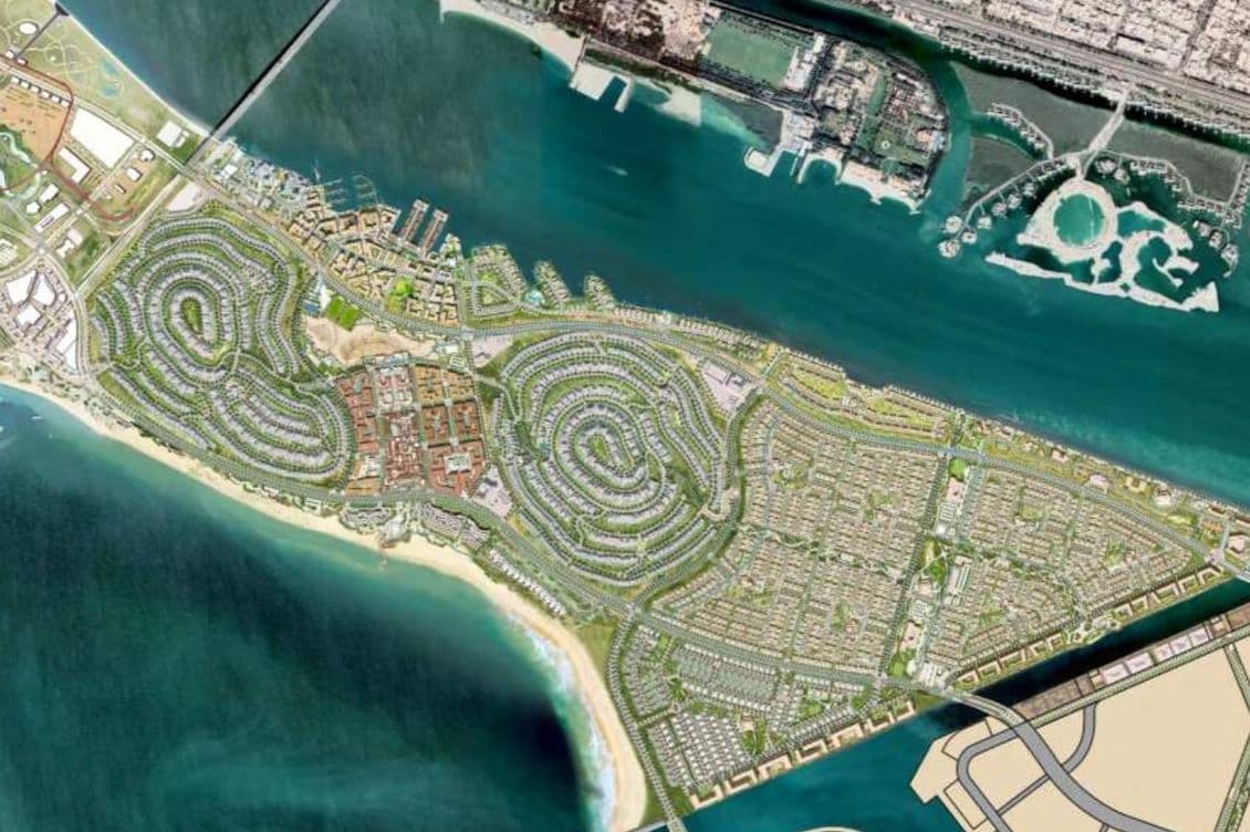 Aerial view of a coastal island development with intricate road patterns, green spaces, and a surrounding ocean, connected to the mainland by a bridge.