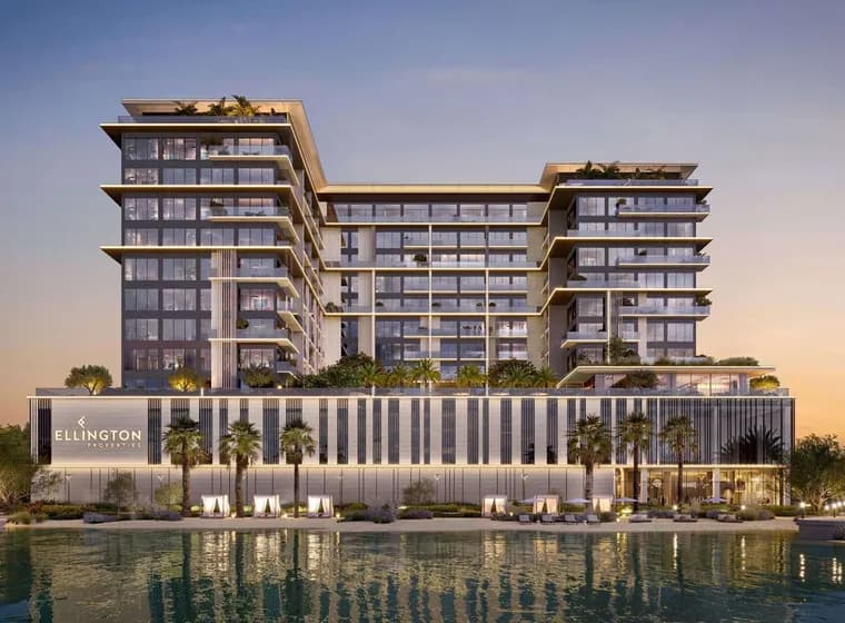 Luxurious glass-fronted, U-shaped waterfront building with stacked balconies, palm trees, and a lit podium reading Ellington Properties at sunset.
