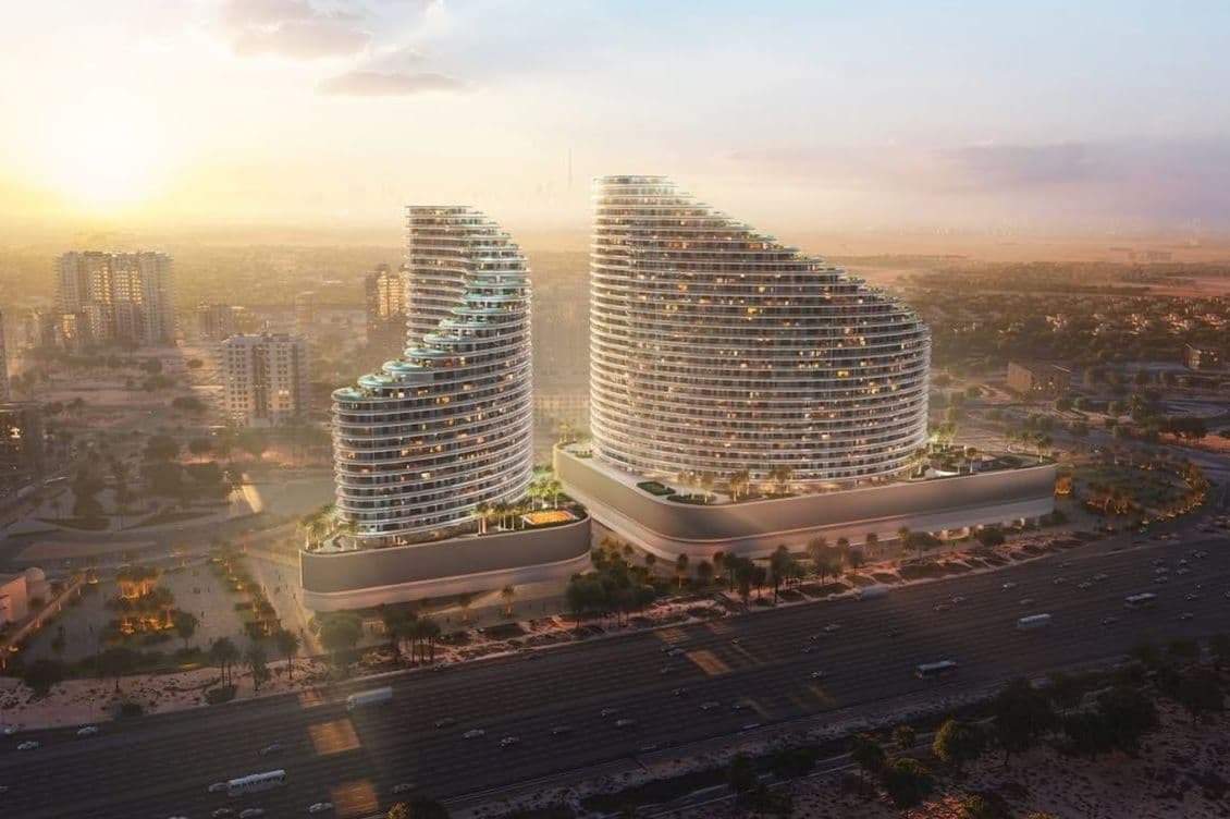 Two modern, curved skyscrapers with rooftop greenery at sunset, surrounded by a sprawling cityscape and highways.