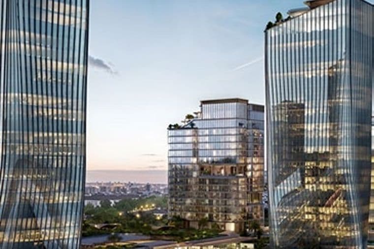 Three modern glass office towers with reflective facades at dusk, mid-rise building with rooftop greenery and distant city skyline.
