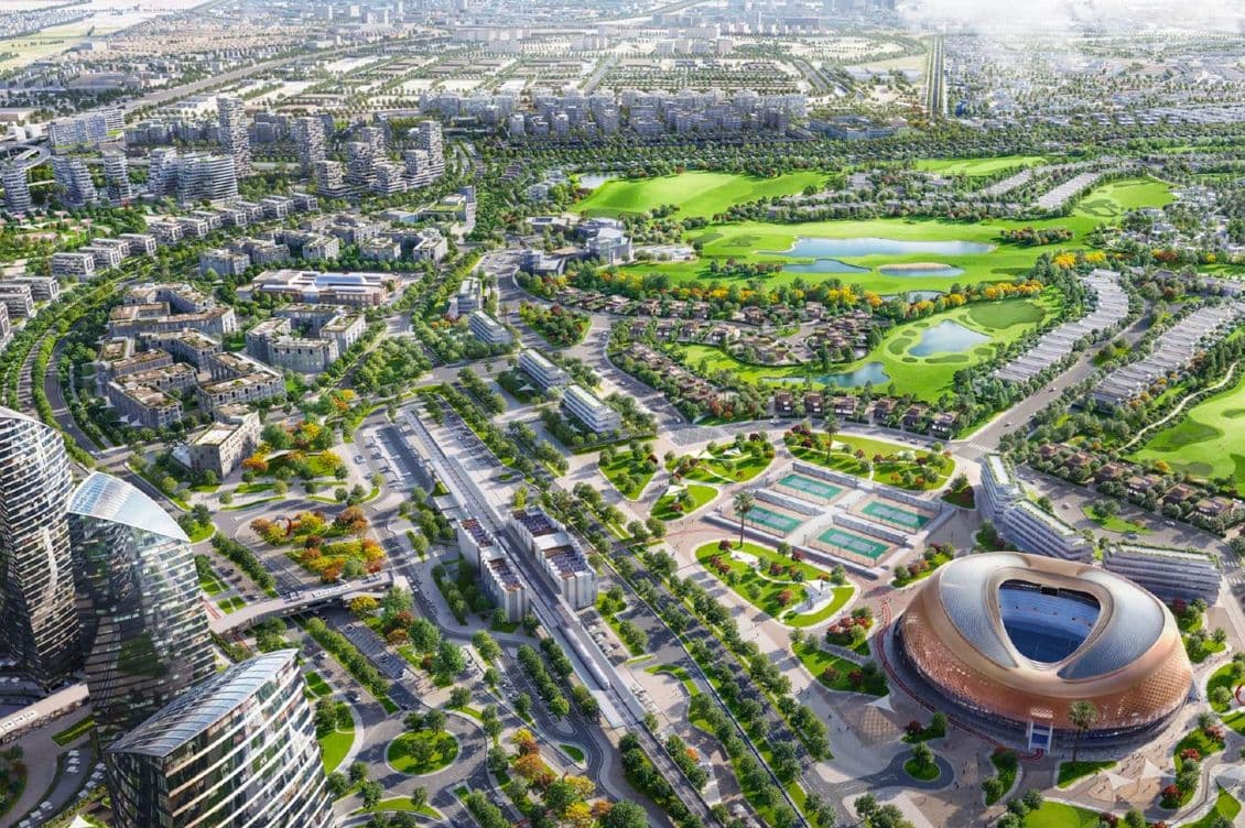 Aerial view of a modern cityscape featuring a stadium, lush green spaces, and residential areas with a network of roads and buildings.