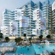 Modern, futuristic residential complex with irregularly stacked glass buildings, surrounded by pools and palm trees at dusk.
