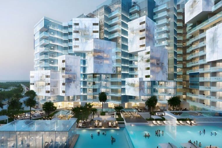 Modern, futuristic residential complex with irregularly stacked glass buildings, surrounded by pools and palm trees at dusk.
