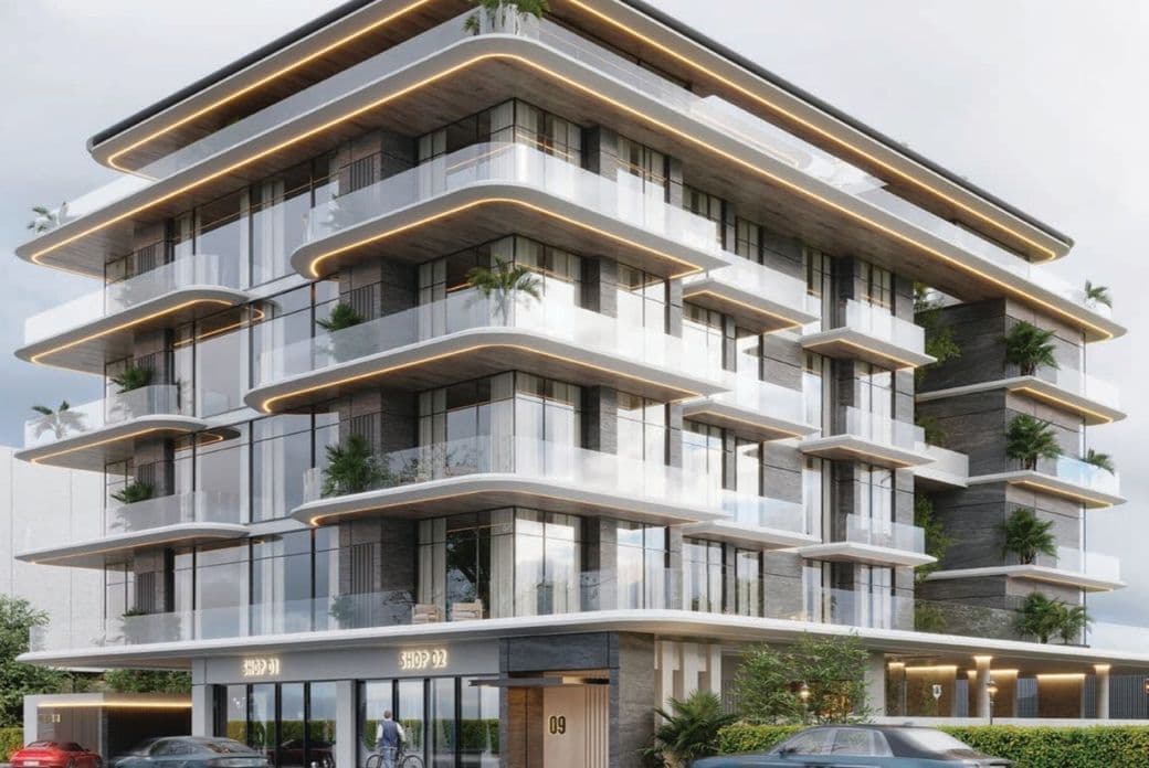 Modern multi-story building with glass balconies, lush plants, and sleek design. Ground level has shop entrances and parked cars in front.