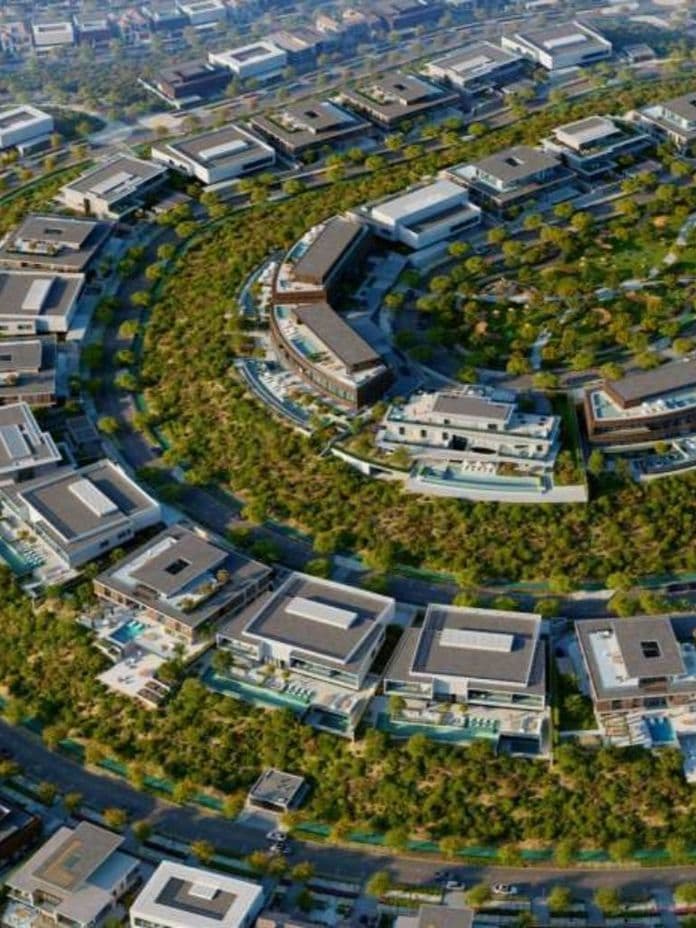 Aerial view of a circular housing complex with modern homes surrounded by green landscapes and curving roads.