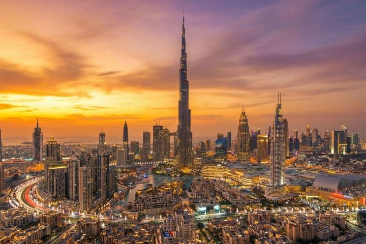 Aerial view of Downtown Dubai at sunset, featuring Burj Khalifa and vibrant orange and purple skies.