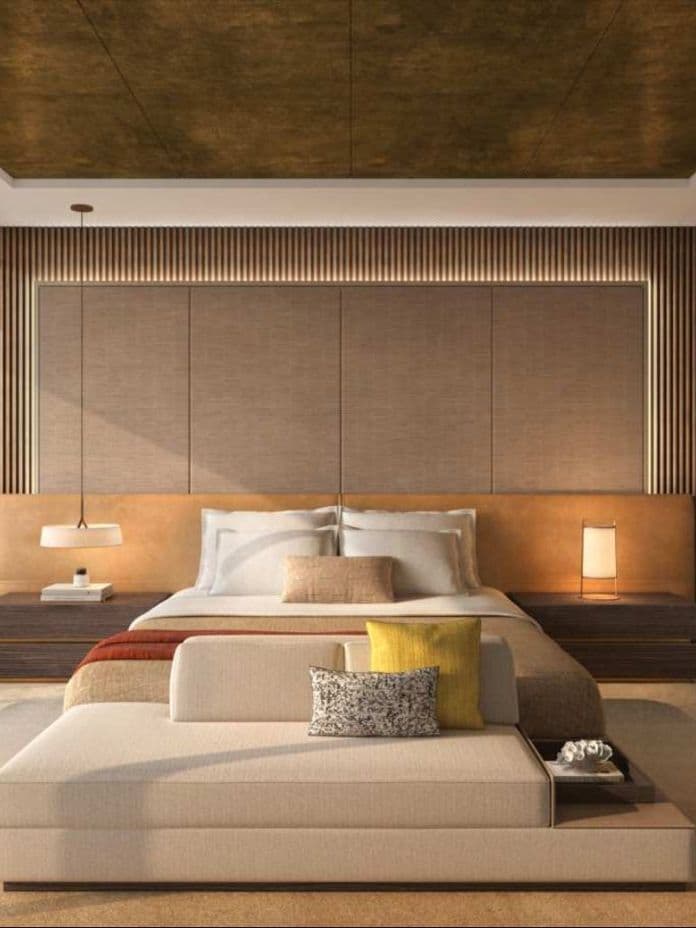 Modern bedroom with a cozy bed, warm lighting, and elegant decor. Floor-to-ceiling windows offer a view of a chair and a serene background.