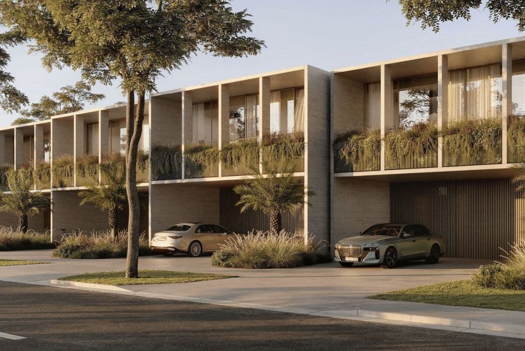 Modern townhouses with large windows and vertical gardens. Two cars parked in driveways, surrounded by trees and landscaped greenery.