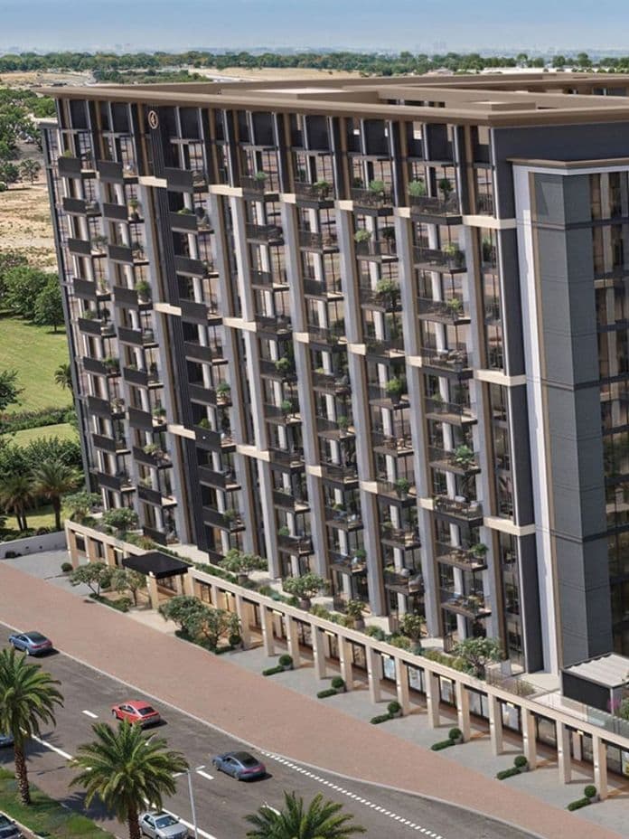 Aerial view of a modern, multi-story residential building with large windows, surrounded by palm trees and a road with passing cars.