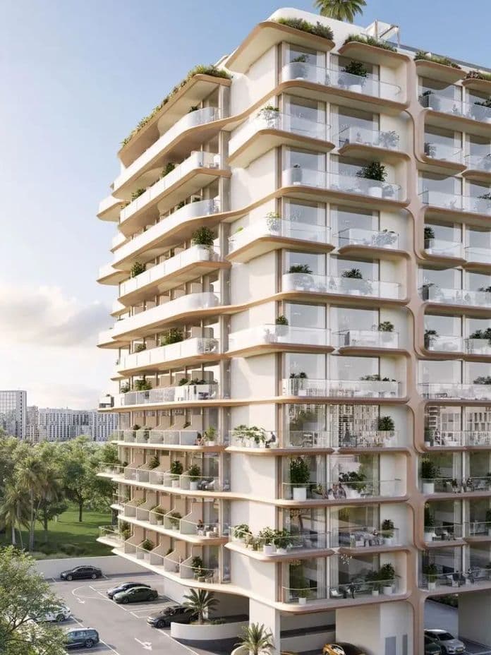 Modern multi-story apartment building with curved balconies, surrounded by greenery and parked cars, under a clear blue sky.
