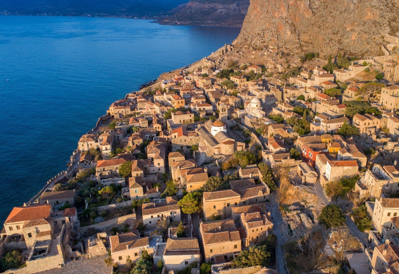 Aerial view of Monemvasia with traditional stone houses, dramatic cliffside landscape, and coastal sea views