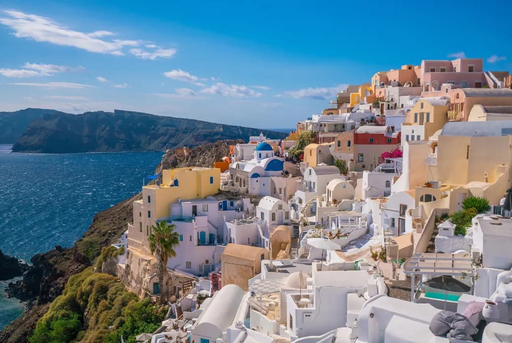 Scenic view of whitewashed houses and blue-domed churches built on the cliffside of Santorini overlooking the Aegean Sea